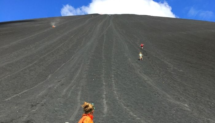 a woman looking up at the side of a volcano after surfing